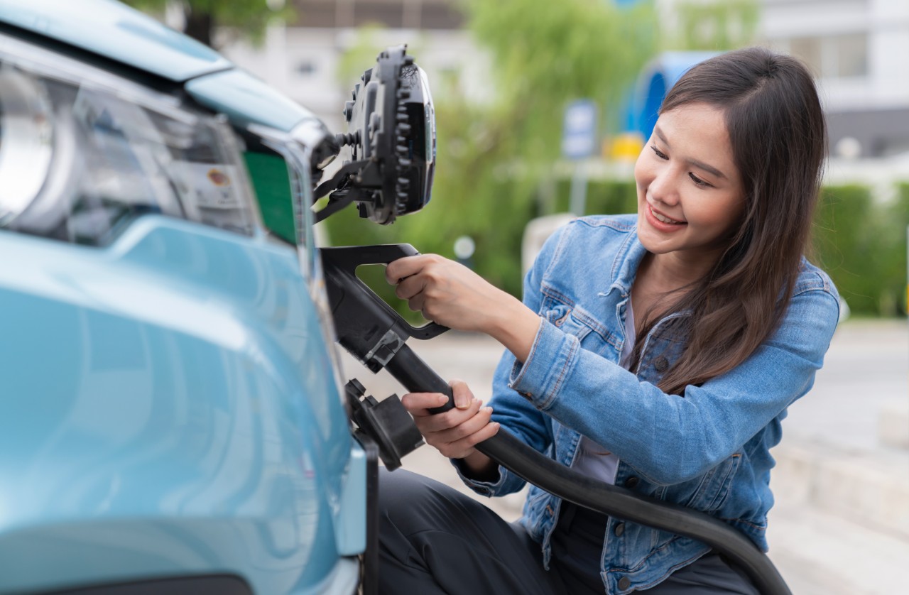 Asia woman holding AC type 2 power cable plug connect to EV car at charging station. Car driven by electric motor engine for clean environment. Rechargeable vehicle concept. Ecology green technology Asia woman holding AC type 2 power cable plug connect to EV car at charging station. Car driven by electric motor engine for clean environment. Rechargeable vehicle concept. Ecology green technology